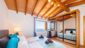 A bedroom with a bed, a nightstand, a lamp, a window, and a sliding glass door leading to a balcony. - Villa "Seaview" with Garden & Wi-Fi (Canyamel)
