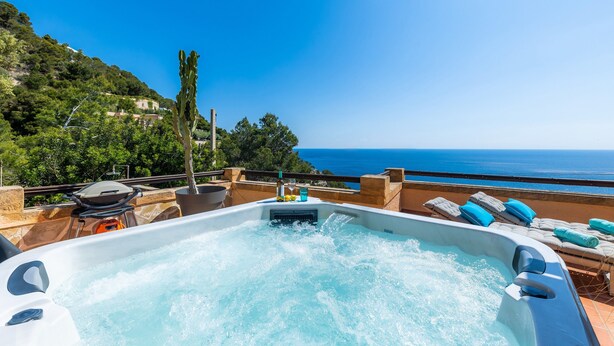 A hot tub with a view of the sea, surrounded by lounge chairs and a patio area. - Villa "Seaview" with Garden & Wi-Fi (Canyamel)
