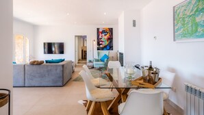 A modern living room with a grey sofa, a glass dining table, and a large abstract painting. - Villa "Seaview" with Garden & Wi-Fi (Canyamel)