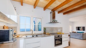 A modern kitchen with a large window, built-in appliances, and a stone backsplash. - Villa "Seaview" with Garden & Wi-Fi (Canyamel)
