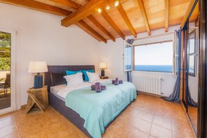 Une chambre à coucher avec un lit, deux lampes de chevet, une vue par la fenêtre et un plafond en bois.