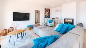 A modern living room with a grey sofa, blue cushions, a flat-screen TV, and a fireplace. - Villa "Seaview" with Garden & Wi-Fi (Canyamel)
