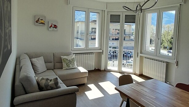 Una sala de estar moderna con un sofá, una mesa de comedor y vistas a través de amplias ventanas.