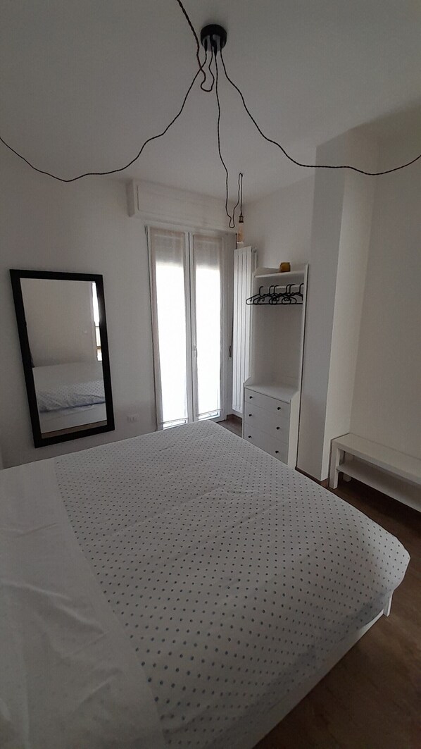 A bedroom with a bed, a mirror, a dresser, and a radiator.