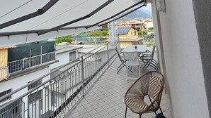 Un balcón con vista a la ciudad, una silla y una mesa.
