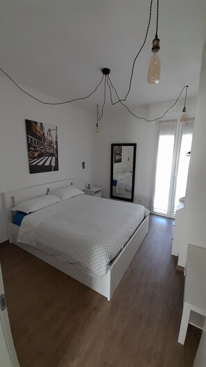 Une chambre à coucher avec un lit, une table de chevet, un miroir et un tableau accroché au mur.