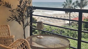 A balcony with wicker furniture, a small table, and a view of the beach and ocean. - Studio Apartment 'Casa Pedro Santa Clara' with Sea View, Pool, and Wi-Fi (Torremolinos)