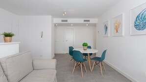 Un salon moderne avec un canapé, une table à manger et des chaises, une plante en pot et des œuvres d’art accrochées aux murs.