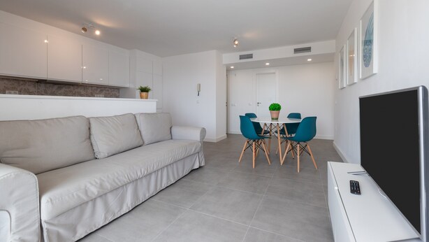 Un salon moderne comprenant un canapé, une table à manger, des chaises et un téléviseur à écran plat.