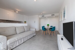 Una sala moderna con sofá, mesa de comedor, sillas y televisor de pantalla plana.