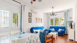 Een woonkamer met twee blauwe banken, een eettafel met stoelen, en een televisie op een kast.