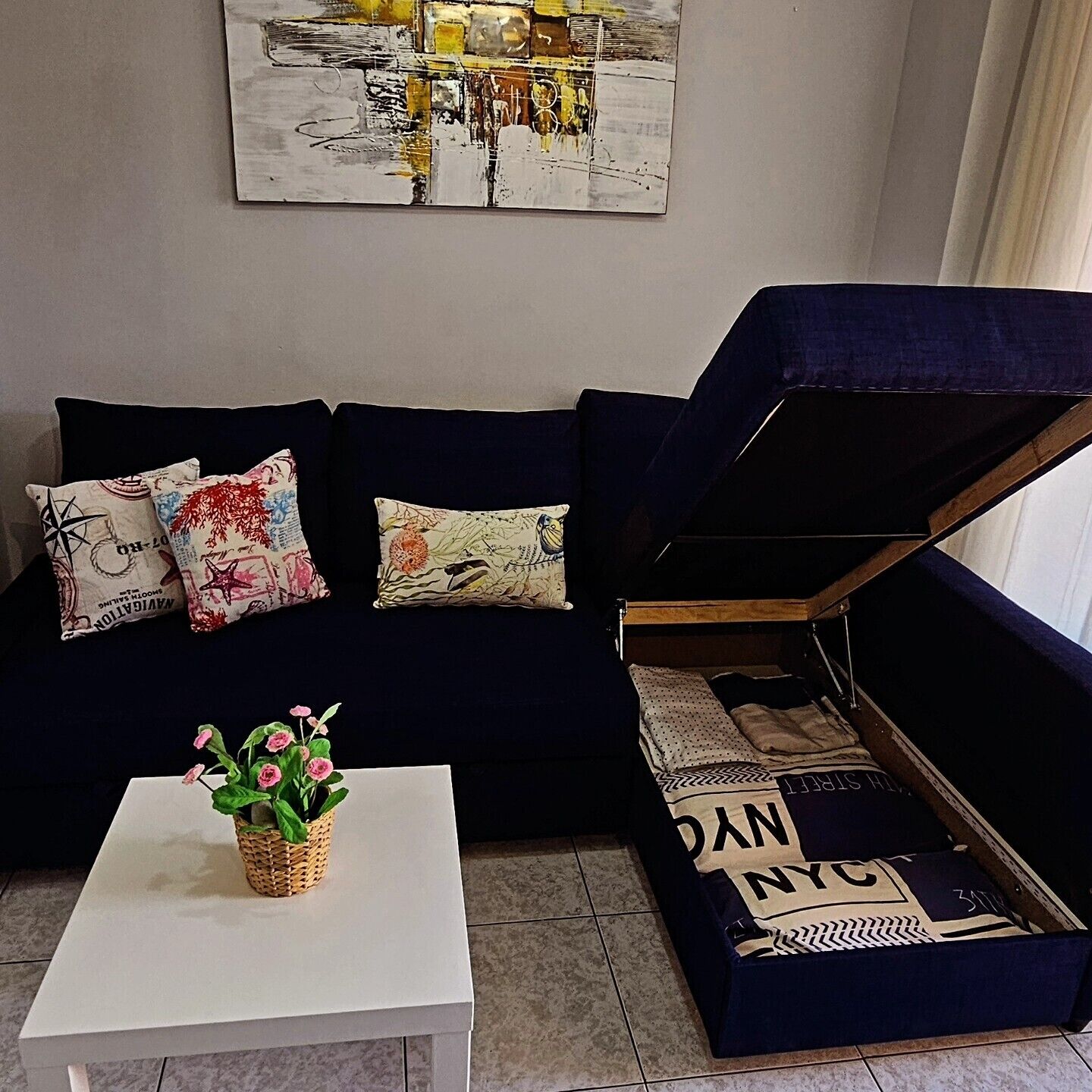 A living room with a dark blue sofa, a white coffee table, and a wall-mounted painting.