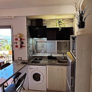 Une cuisine compacte équipée d’un lave-linge, un coin repas avec vue et une petite table à manger.