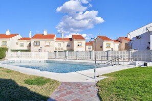 A swimming pool with a tiled deck, surrounded by a white fence, and houses with red roofs in the background. - Holiday Apartment 'Casa Venus' with Sea View, Terrace, Shared Pool & Wi-Fi (Salobrena)