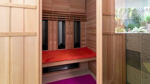 Una sauna de madera con un banco, una ventana y vistas al jardín exterior.