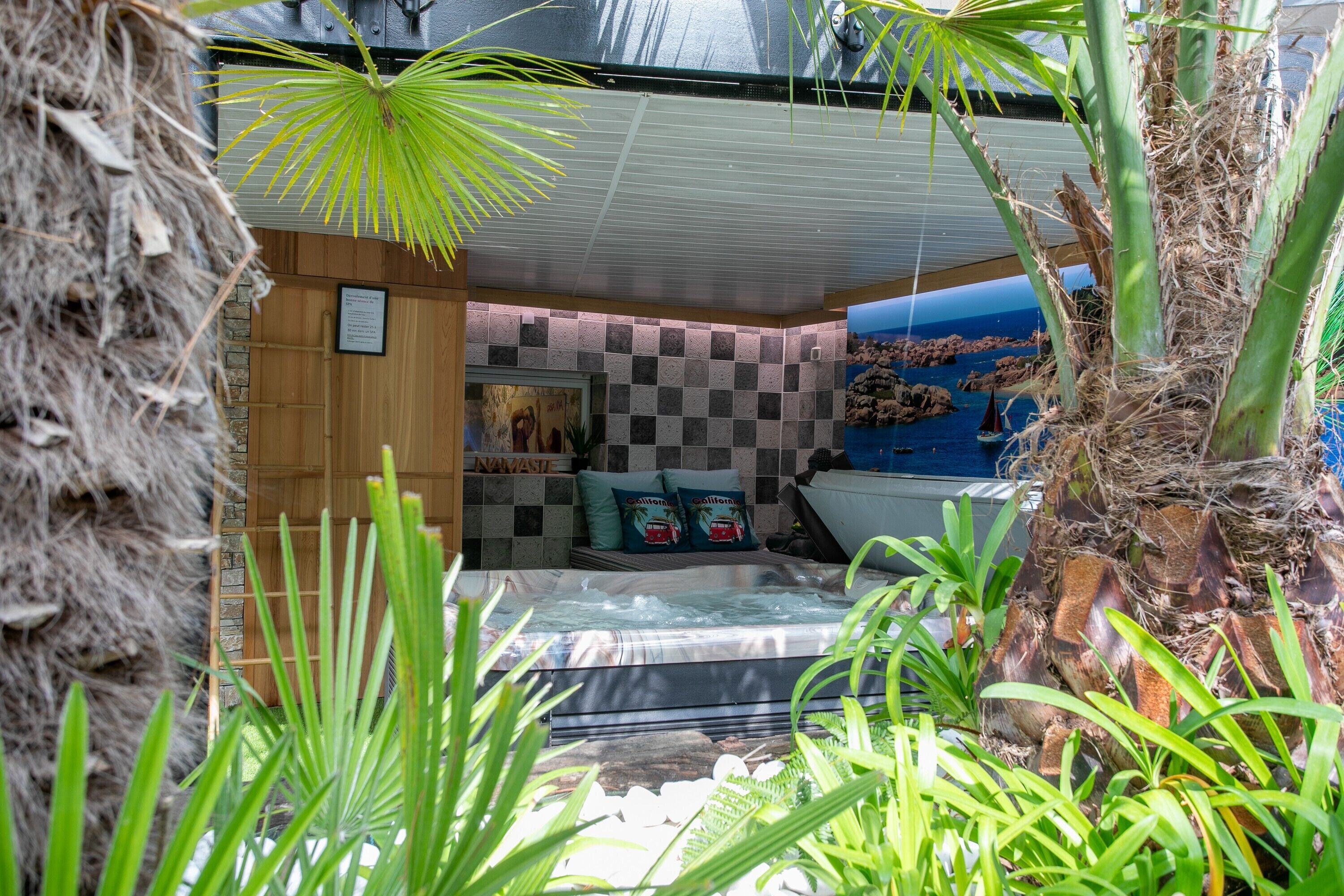 Une salle de spa dotée d’un jacuzzi, de murs en bois et de plantes tropicales.