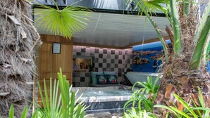 Un cuarto de spa con un jacuzzi, paredes de madera y plantas tropicales.