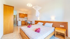 Een hotelkamer met een bed, nachtkastje en een klein kitchenette.