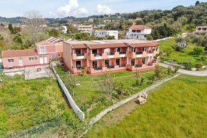 Un immeuble résidentiel à plusieurs étages, doté de balcons, entouré de champs verdoyants et d’arbres.