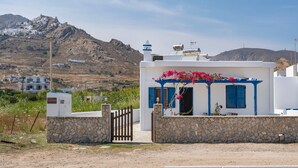 Un bâtiment blanc avec des volets bleus, un mur de pierre et un portail.