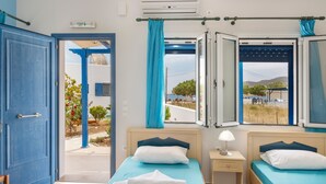 Ein Zimmer mit zwei Betten, einem Fenster mit Vorhängen, einem Nachttisch und einer Klimaanlage.
