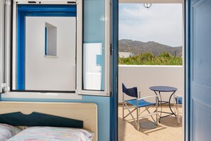 Une chambre avec un lit, une fenêtre et un balcon équipé d’une table et de chaises.