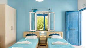 Une chambre avec deux lits, une armoire, une fenêtre avec des rideaux et une porte.