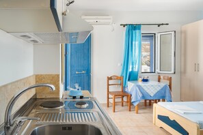 Une cuisine compacte équipée d’un évier, d’une cuisinière et d’un coin repas avec une table et des chaises.