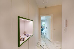 Un couloir avec un miroir, une porte donnant sur une salle à manger et un téléphone fixé au mur.