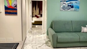 A hallway with a marble floor, a green sofa, and two wall art pieces. - Apartment 'Gio Mar Green' with Mountain View, Wi-Fi and Air Conditioning (Piano di Sorrento)
