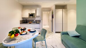 A modern kitchen with a dining area, a green sofa, and a marble floor. - Apartment 'Gio Mar Green' with Mountain View, Wi-Fi and Air Conditioning (Piano di Sorrento)