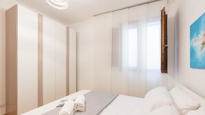 Un dormitorio moderno con una cama, cama con toallas ordenadas, un cuadro en la pared y una puerta corrediza.