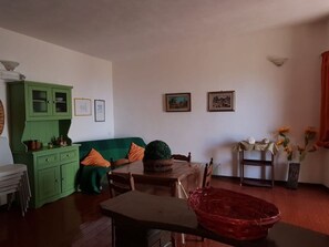 Un comedor con una mesa, sillas, un armario verde y una cesta roja.