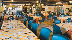 A restaurant with multiple tables, chairs, and a kitchen area in the background.