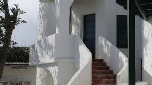 A white building with a staircase leading to a dark door.