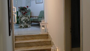 Eine Treppe führt in ein Wohnzimmer mit einem grünen Sessel, einem Tisch mit Blumenmuster und Wandbildern.
