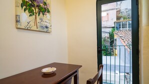 Una habitación con un escritorio de madera, una silla, una puerta con reja metálica y una pared decorada con un cuadro floral.