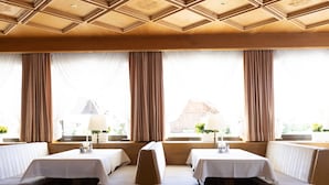 Un espace repas avec des banquettes en bois, des nappes blanches et un plafond en bois.