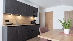 Une cuisine moderne avec des meubles de couleur sombre, un plan de travail en bois, un four à micro-ondes encastré et une machine à café.