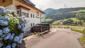 A building with a name sign, a parked vehicle, and a view of green hills. - Apartment "Haus Reimon Monika" with Mountain View & Wi-Fi (St.Leonhard in Passeier)