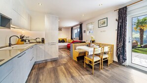 A modern kitchen with a central island, a dining area with a table and chairs, a sofa, and a large sliding glass door leading to a balcony with a view. - Apartment "Haus Reimon Monika" with Mountain View & Wi-Fi (St.Leonhard in Passeier)