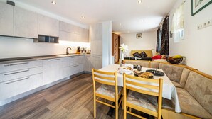 A modern kitchen with a dining area, wooden chairs, a table, and a sofa. - Apartment "Haus Reimon Monika" with Mountain View & Wi-Fi (St.Leonhard in Passeier)