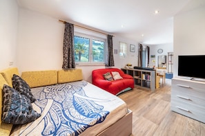 A modern hotel room with a large bed, a red sofa, a TV, and a desk area. - Apartment "Haus Reimon Monika" with Mountain View & Wi-Fi (St.Leonhard in Passeier)
