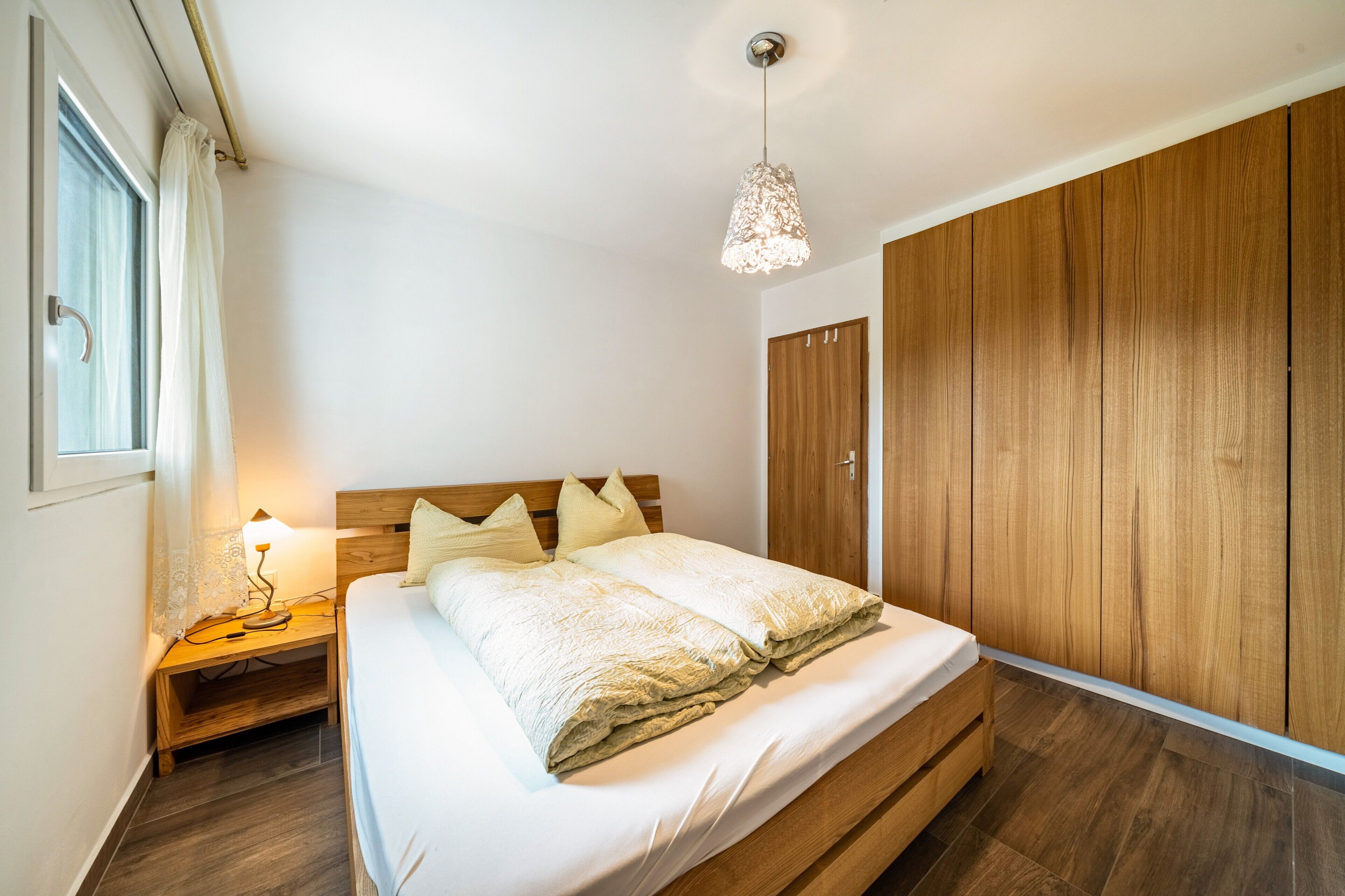 Camera da letto con un letto, un'armadiatura in legno e una lampada da comodino.
