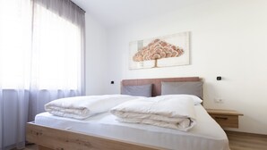 Uma cama bem arrumada com estrutura de madeira, uma mesa de cabeceira com gaveta e uma obra de arte pendurada na parede.