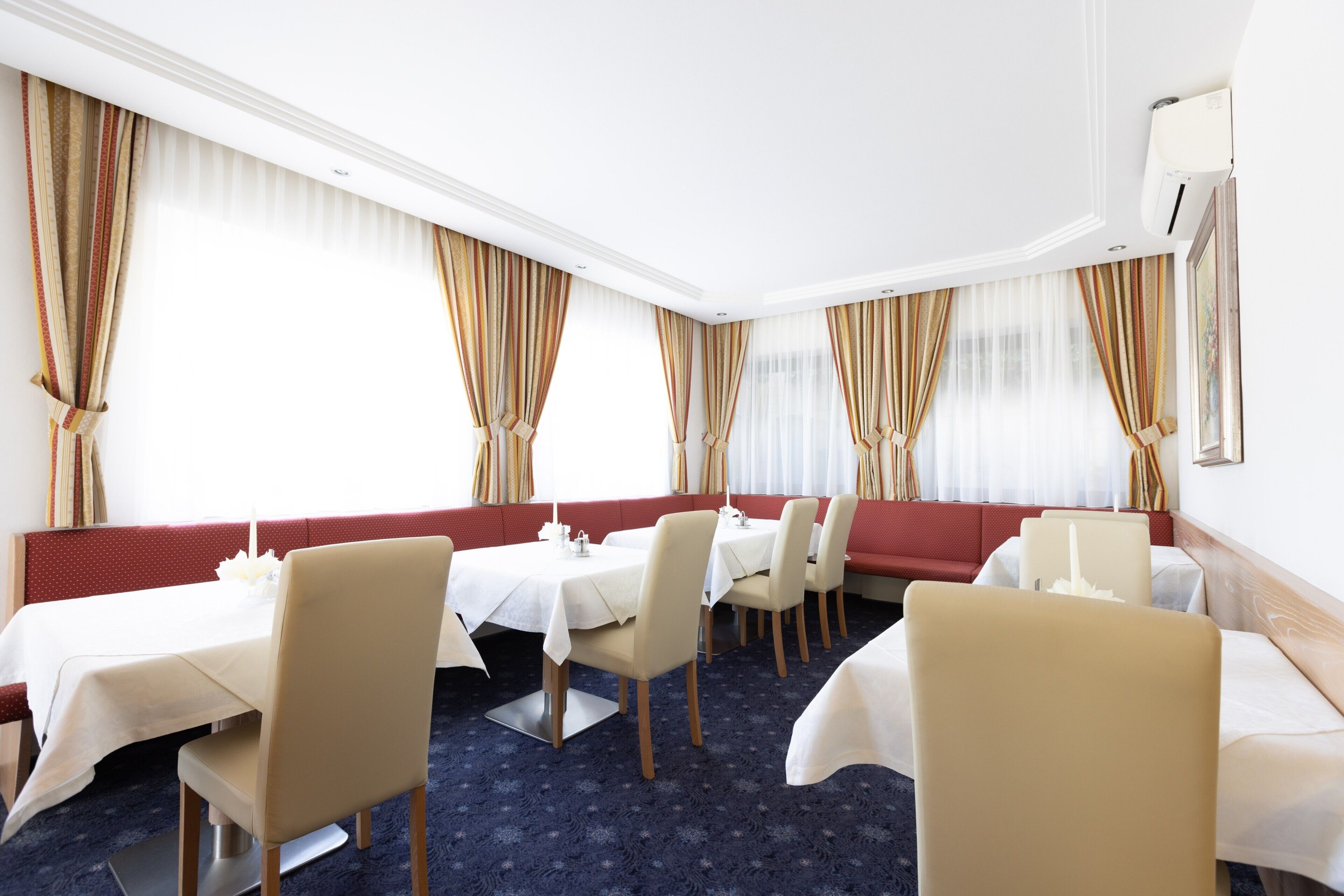 Ein Hotelzimmer mit Essbereich, einem roten Sofa und einem großen Fenster mit Vorhängen.