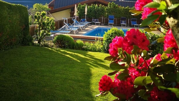 A pool area with lounge chairs, a building with a sloped roof, and a mountainous backdrop. - Apartment "Kleon 2" with Mountain View, Shared Pool and Wi-Fi (Riffian)