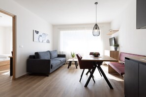 Un espace de vie moderne comprenant un canapé, une table à manger et une kitchenette.