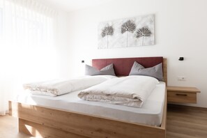 Un lit avec un cadre en bois, une tête de lit rouge et du linge de lit blanc.
