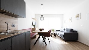 A modern kitchen with a dining area, a gray sofa, and a hanging light fixture. - Holiday Apartment "Kleon 3" with Mountain View, Shared Pool and Wi-Fi (Riffian)